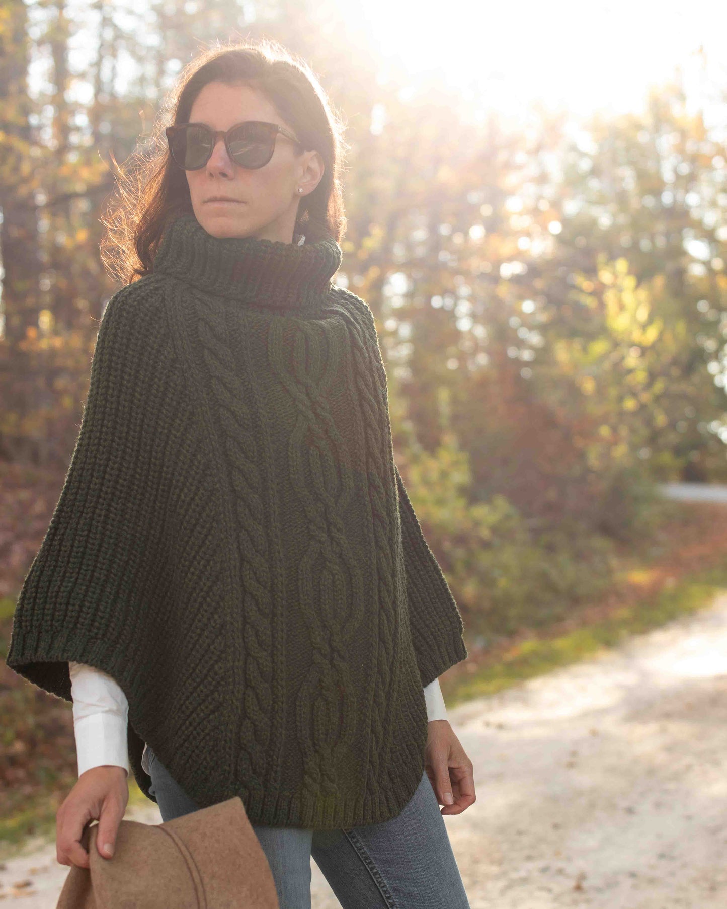 Woman wearing a dark green poncho in a forest setting