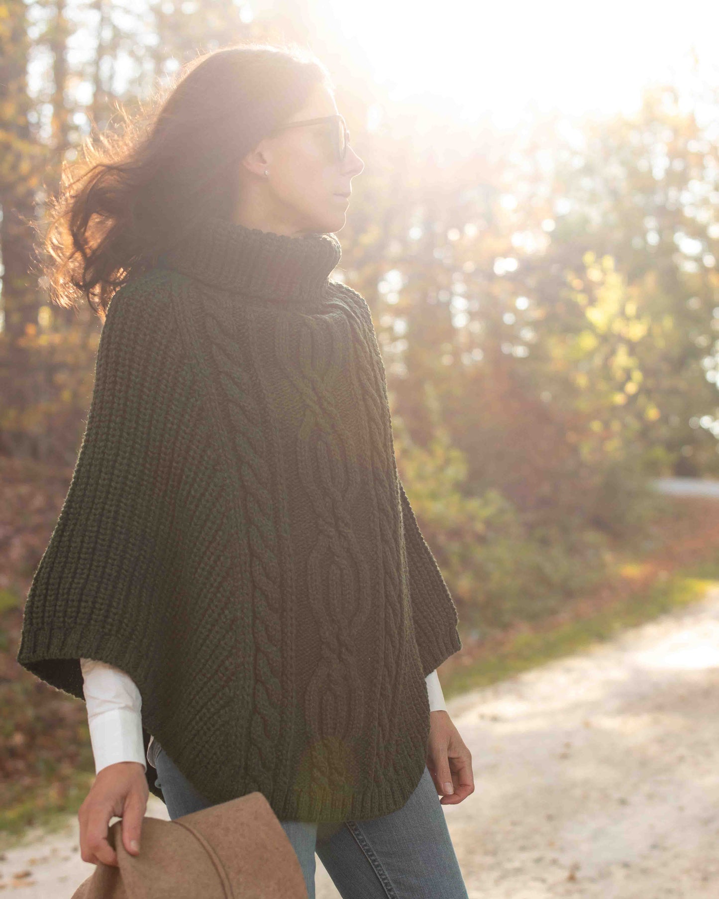 Woman wearing a dark green poncho in a forest setting
